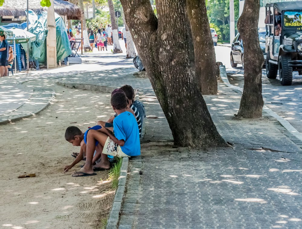 Adulto e criança conversando sentados sob uma árvore