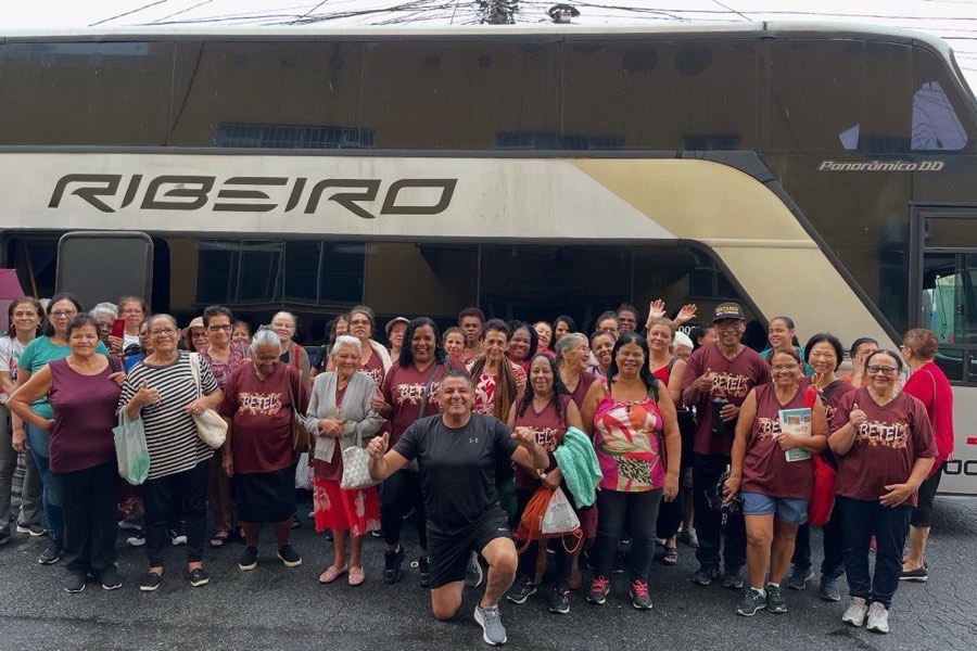 Grupo da 3ª idade em frente ao ônibus do passeio